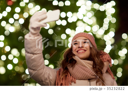 young woman taking selfie over christmas tree 35232822