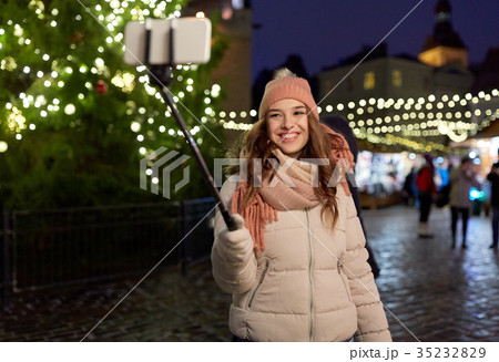 young woman taking selfie over christmas tree young woman taking selfie over christmas tree 35232829