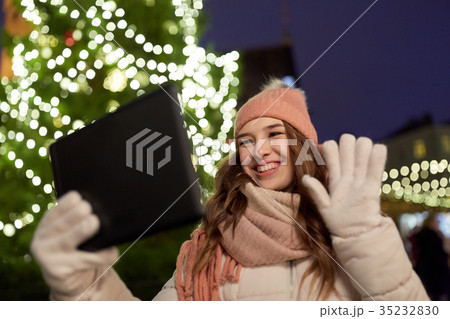 woman with tablet pc at christmas tree outdoors woman with tablet pc at christmas tree outdoors 35232830