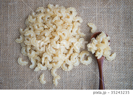 Short, curved and ruffled raw pasta on rustic 35243235