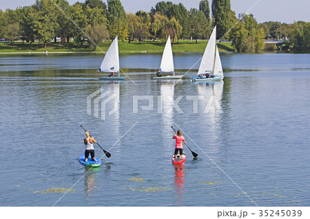 Two women on paddle board and three boat sailling 35245039