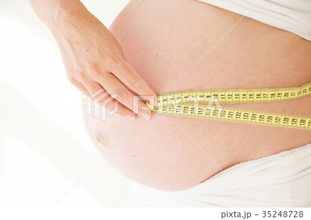 the stomach of a pregnant woman and a measuring 35248728
