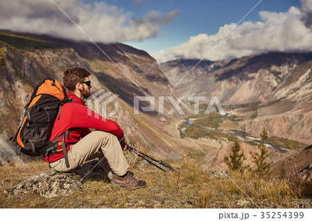 Handsome young male hiker sitting on the edge of a Handsome young male hiker sitting on the edge of a 35254399
