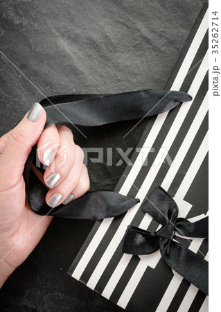 Female hand holding a package in white and black Female hand holding a package in white and black 35262714
