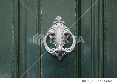 Vintage antiqued door knocker on wooden green door Vintage antiqued door knocker on wooden green door 35266821