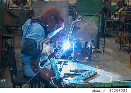 Man is welding an automotive part. 35268521