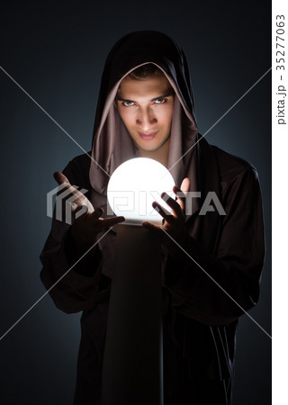 Young wizard with crystal ball in dark room 35277063