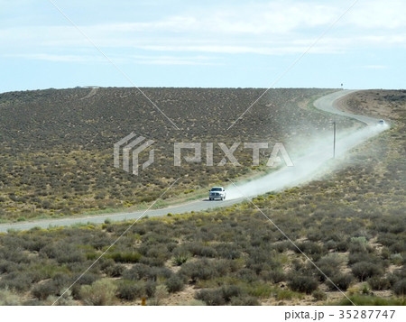 アメリカの荒野を土煙をあげて走る車の写真素材