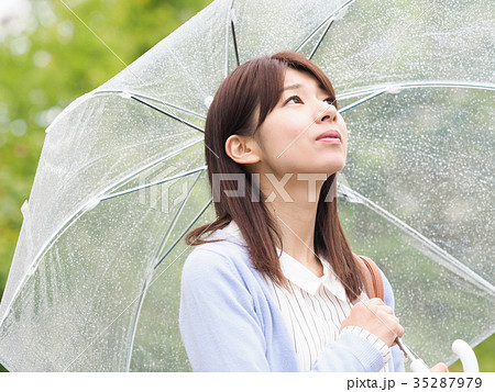 公園で傘をさして空を見上げる女性の写真素材