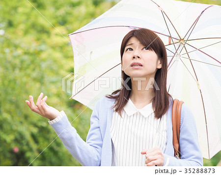 傘をさして空を見上げる女性の写真素材
