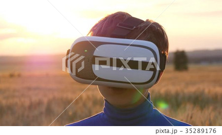 A boy stands in a wheat field at sunset in virtual A boy stands in a wheat field at sunset in virtual 35289176
