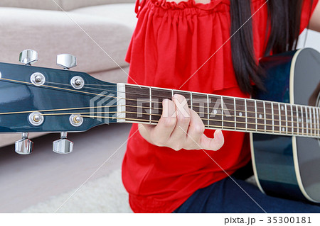 ギターを弾く若い女性 顔なしの写真素材