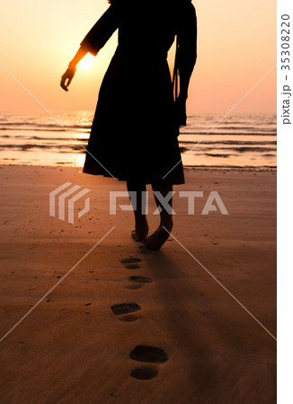 Woman walking towards seaside at sunset 35308220