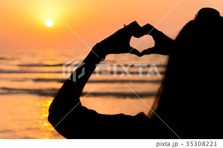 Girl making heart shape at seaside 35308221