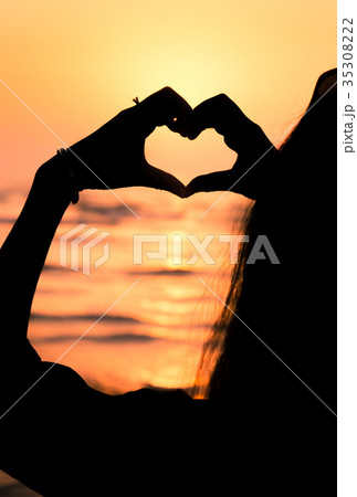 Girl making heart shape at seaside 35308222