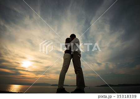 シルエット 抱き合いキスするふたりの写真素材