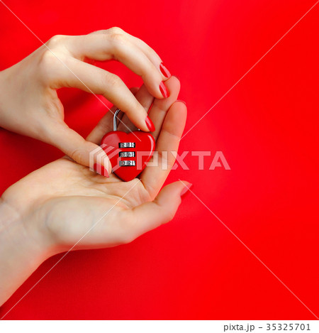 Padlock heart-shape in women's hands on red 35325701