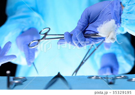 Surgeons hands holding surgical scissors and Surgeons hands holding surgical scissors and 35329195