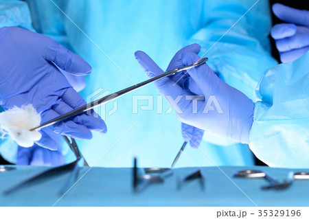 Surgeons hands holding surgical scissors and Surgeons hands holding surgical scissors and 35329196