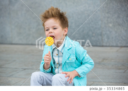 Fashion kid with lollipop near gray wall Fashion kid with lollipop near gray wall 35334865