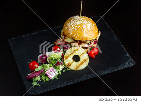 Hamburger with pineapple lies on a black slate Hamburger with pineapple lies on a black slate 35336543
