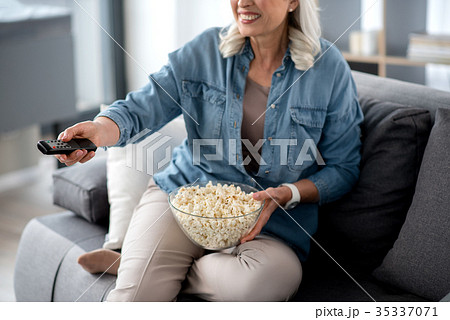 Joyful senior lady eating snack during interesting 35337071