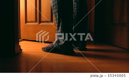 Adult man stands near door to a bathroom at night 35343005