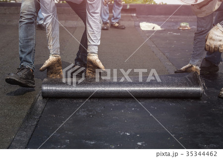 Group of worker installing tar foil on the rooftop of building. Waterproof system by gas and fire torching 35344462