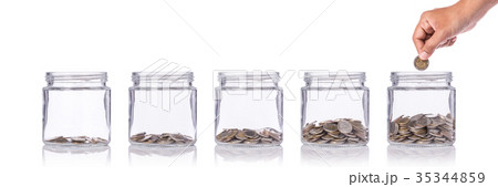 Hand holding Thai coin (baht) and insert to clear glass jar. Studio shot isolated on white. Save money or investment financial for future concept Hand holding Thai coin (baht) and insert to clear glass jar. Studio shot isolated on white. Save money or investment financial for future concept 35344859