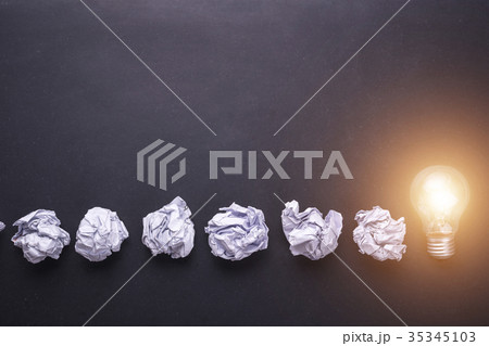 Top view crumpled paper and light bulbs on black stone board. Create idea concept Top view crumpled paper and light bulbs on black stone board. Create idea concept 35345103