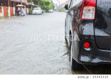 Car parking on the street of village while raining and show level of water flooding 35345310