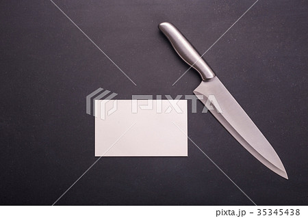 Stainless steel cooking knife on black stone background. Top view with free space and paper note for text or design Stainless steel cooking knife on black stone background. Top view with free space and paper note for text or design 35345438