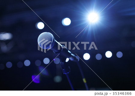 Close up of microphone in concert hall or conference room with cold lights in background. 35346366
