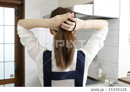髪を束ねる女性の後ろ姿 の写真素材