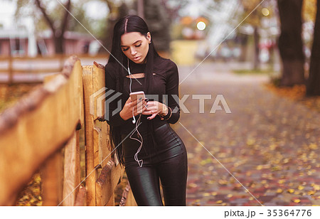 Brunette young woman listening to music in autumn 35364776