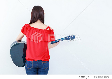 立ってギターを弾く若い女性 後姿の写真素材