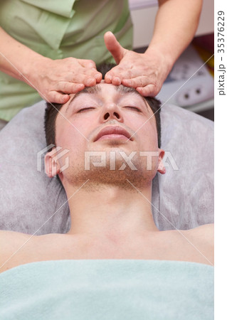 Handsome man getting face massaged. 35376229