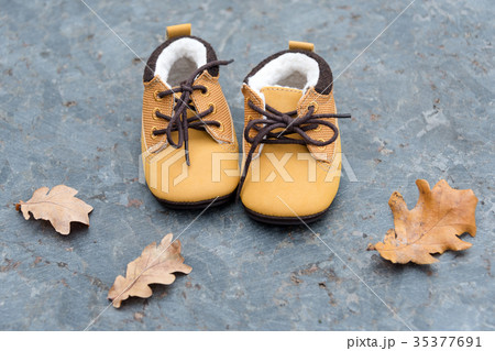 Baby boots in forest. Kid shoes with autumn leaves Baby boots in forest. Kid shoes with autumn leaves 35377691