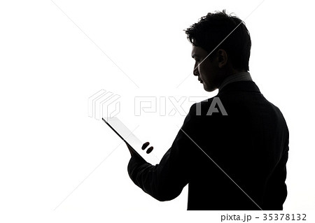 タブレットを見る男性シルエットの写真素材