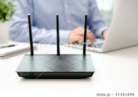 Wireless router and man using a laptop in office Wireless router and man using a laptop in office 35381896