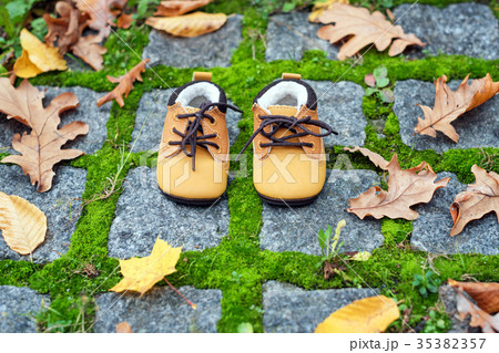 Baby boots in autumn park. Kid shoes with yellow Baby boots in autumn park. Kid shoes with yellow 35382357