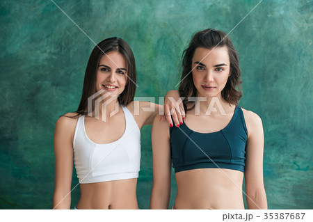 Two young sporty women posing at gym. Two young sporty women posing at gym. 35387687