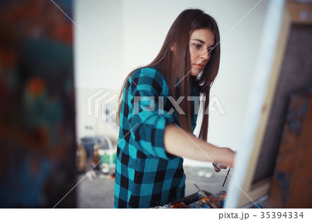 Young artist girl at work in the workshop brush paints canvas inspiration Young artist girl at work in the workshop brush paints canvas inspiration 35394334
