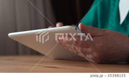 Close up of a white tablet PC in aged woman hands Close up of a white tablet PC in aged woman hands 35398155