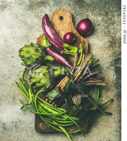 Flat-lay of green and purple vegetables on board 35404582