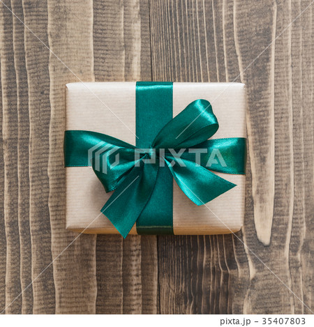 Gift box wrapped in craft paper with green ribbon. 35407803