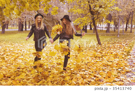 Two cheerful girls in hats walking in autumn park 35413740