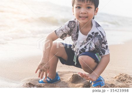 Happy boy is playing with sand on a beach Happy boy is playing with sand on a beach 35423998