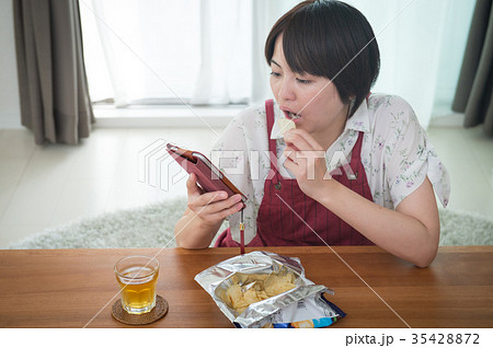 スマホを見ながらお菓子を食べる主婦 ながら食い スマホを見ながらお菓子を食べる主婦 ながら食い 35428872