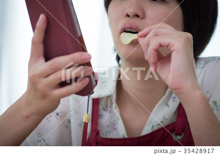 スマホを見ながらお菓子を食べる主婦　若い女性 35428917